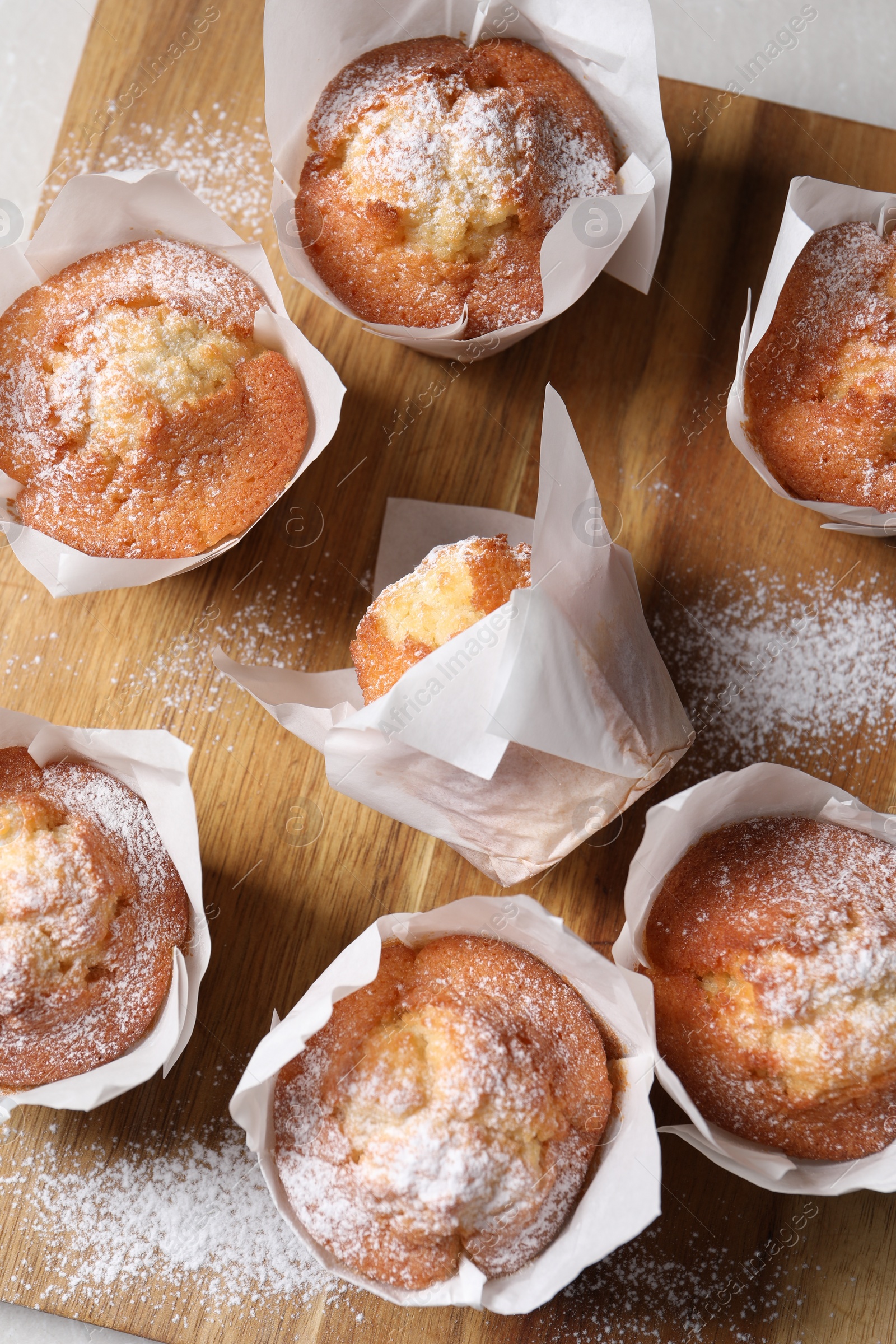 Photo of Delicious muffins on wooden board, top view