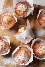 Delicious muffins on wooden board, top view