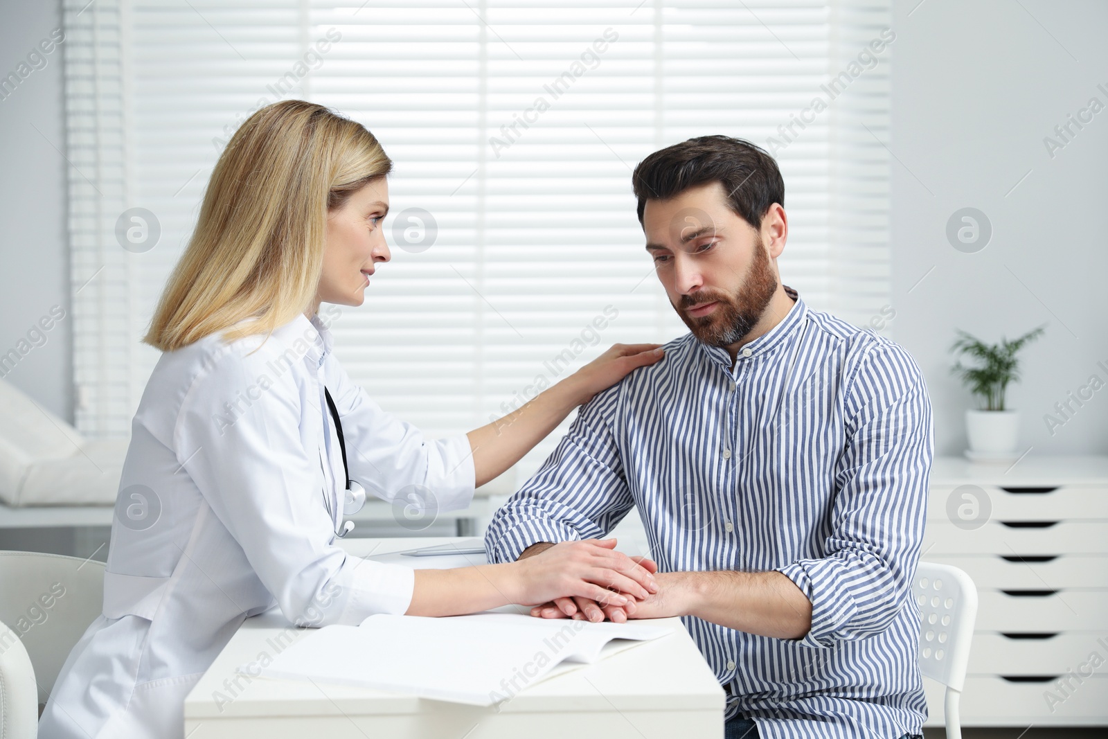 Photo of Doctor consulting patient at white table in clinic