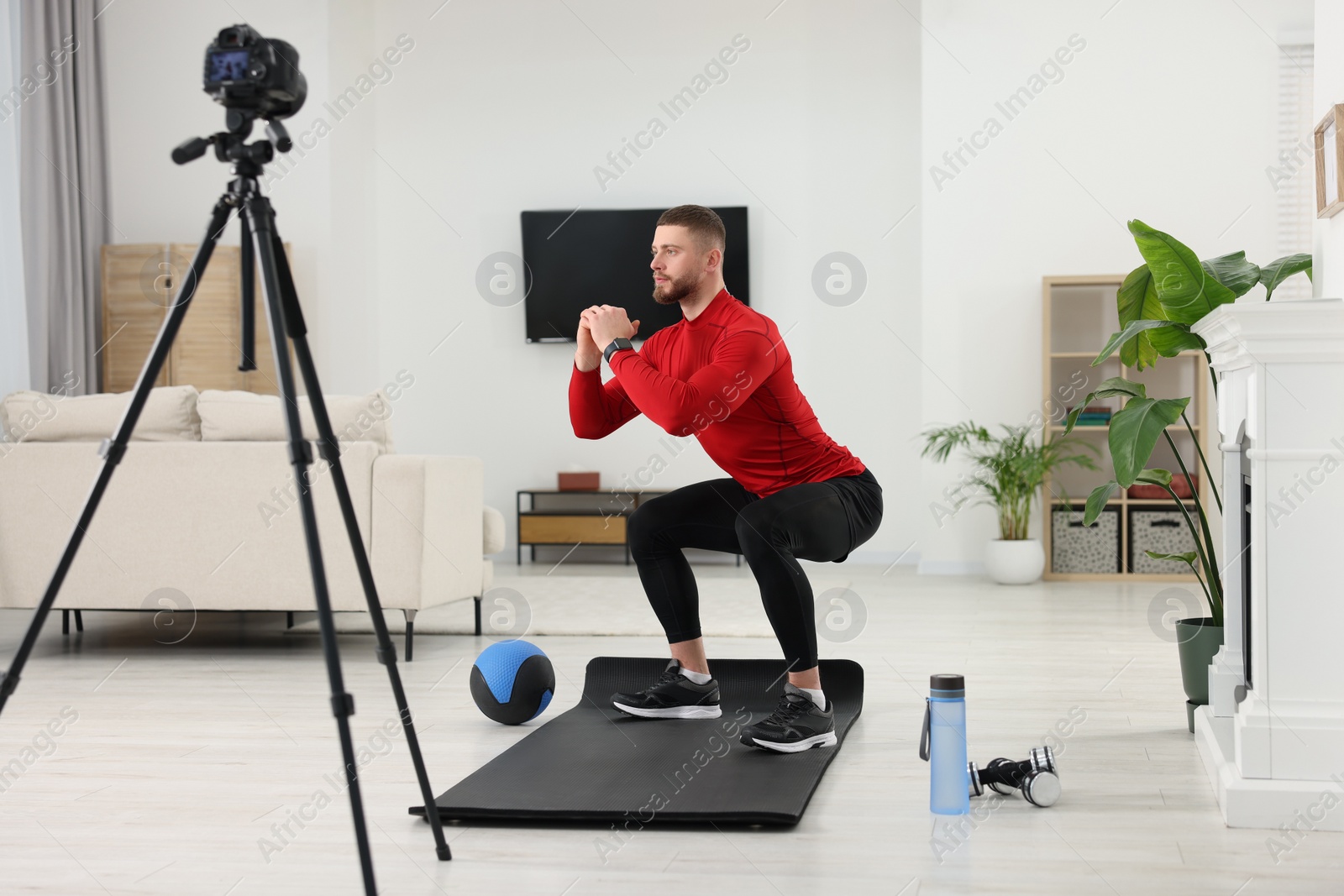 Photo of Trainer recording workout on camera at home