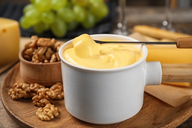 Pot of tasty cheese fondue and products on wooden table