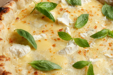 Delicious cheese pizza with basil as background, closeup
