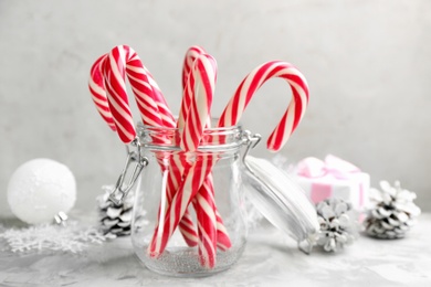 Photo of Many sweet candy canes in glass jar on light table. Traditional Christmas treat