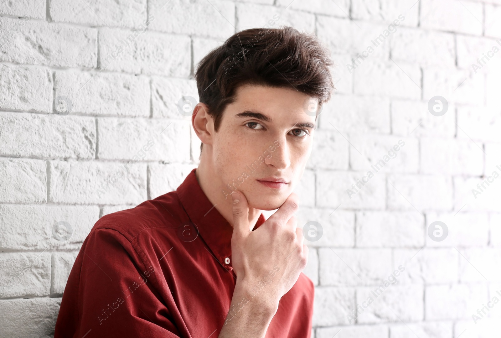 Photo of Portrait of young man with beautiful hair on brick wall background