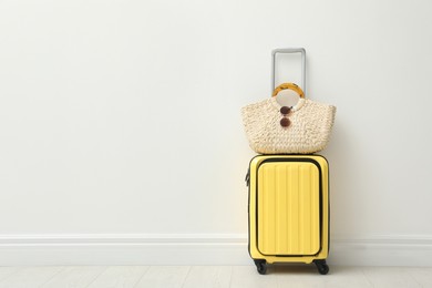 Packed suitcase and summer accessories near white wall indoors. Space for text