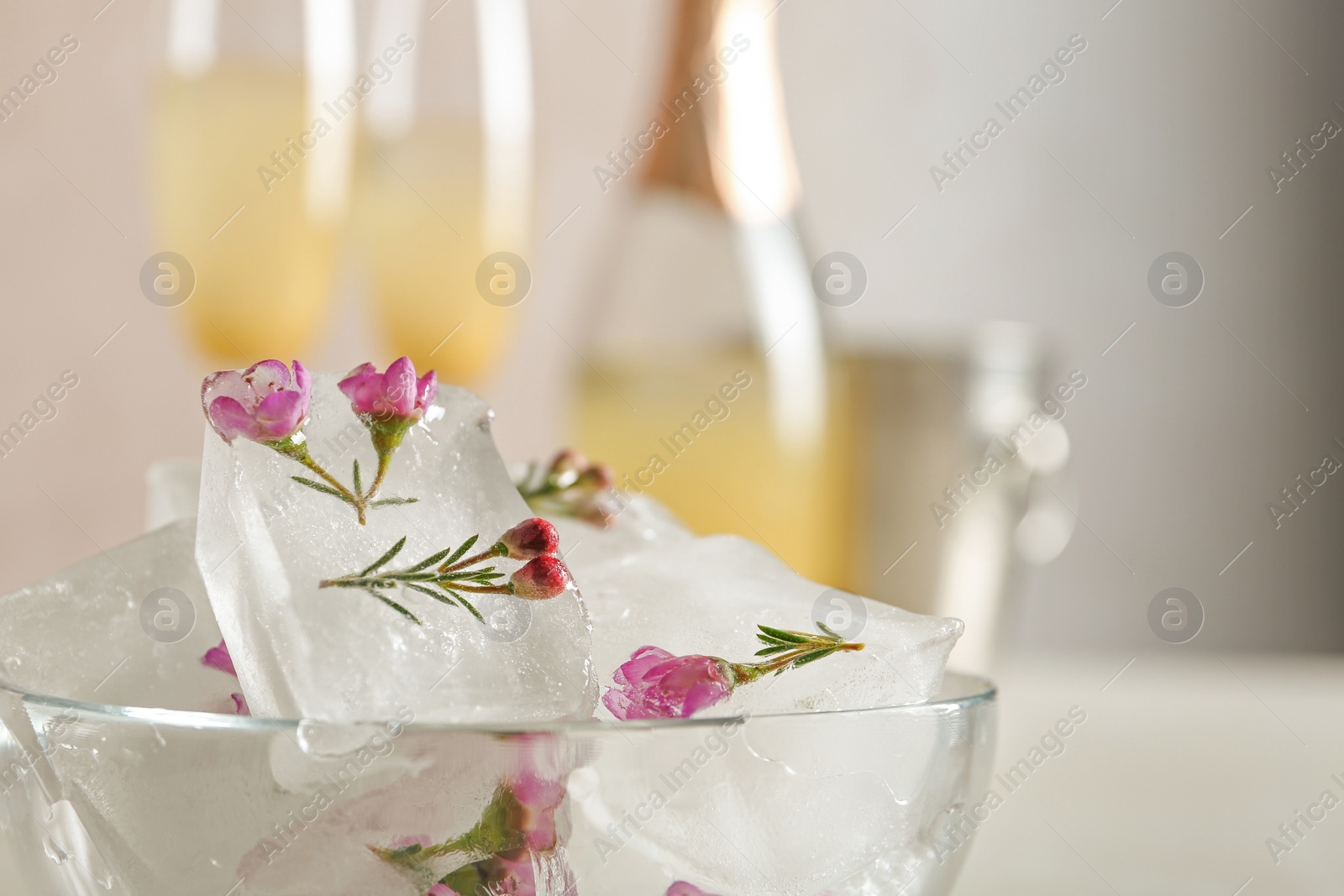 Photo of Bowl with floral ice cubes on blurred background, closeup. Space for text