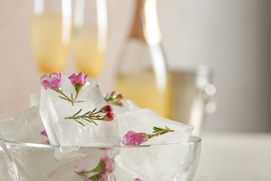 Photo of Bowl with floral ice cubes on blurred background, closeup. Space for text