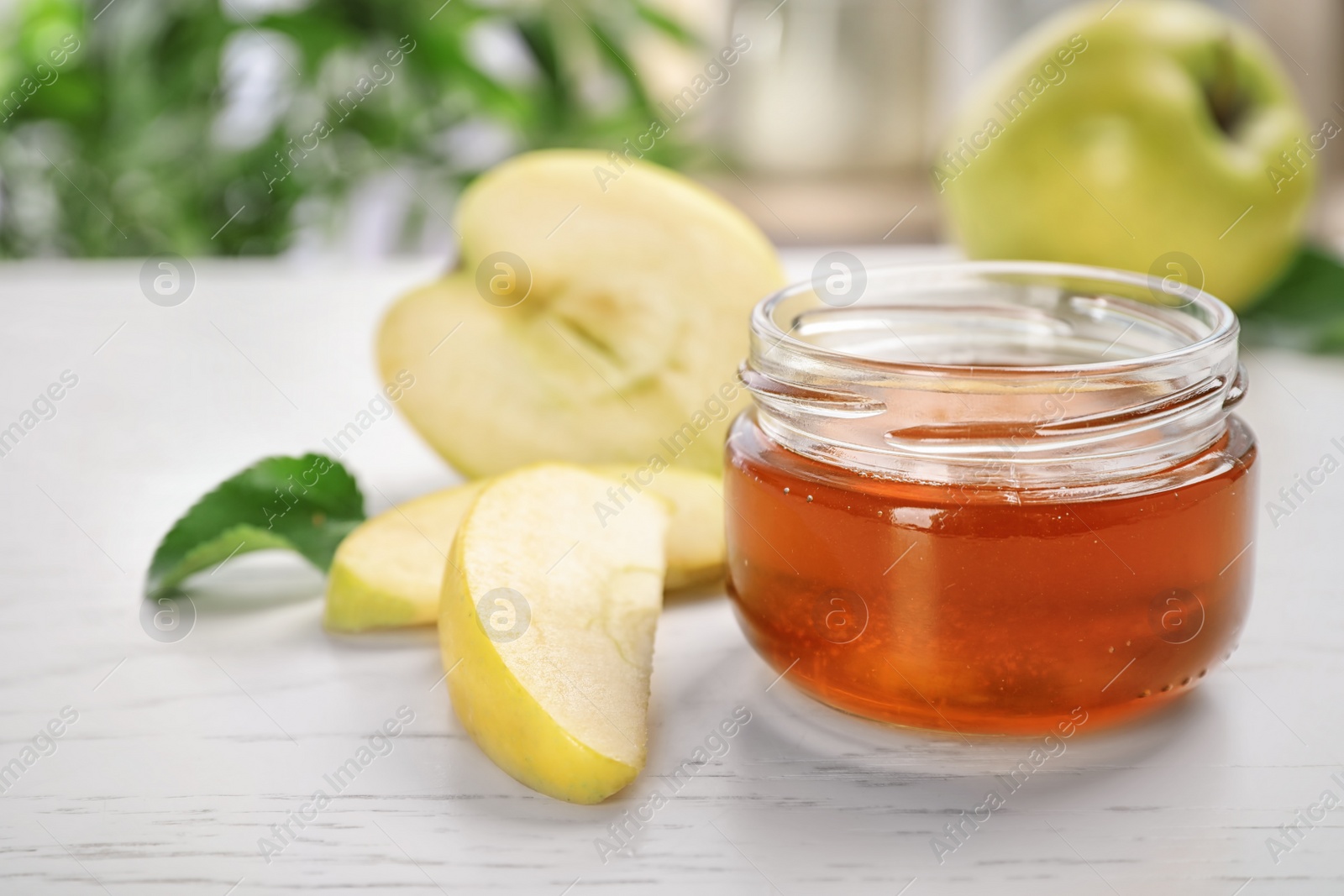 Photo of Jar of honey and apples on light table