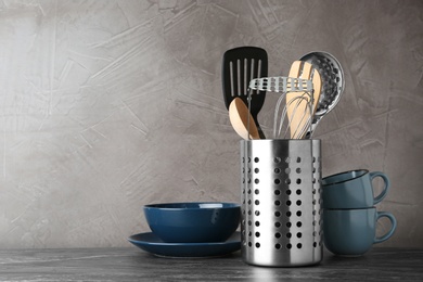 Holder with kitchen utensils on grey table against grey stone background. Space for text