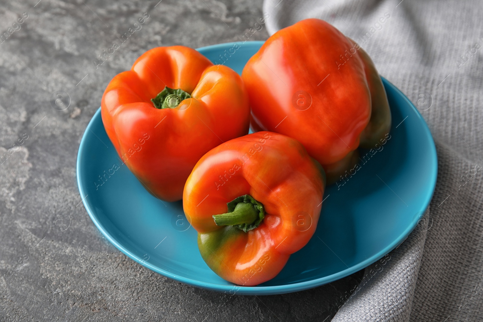 Photo of Plate with ripe paprika peppers on grey background