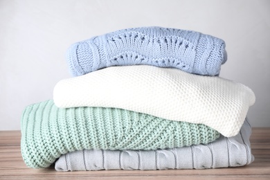 Stack of folded warm sweaters on wooden table 