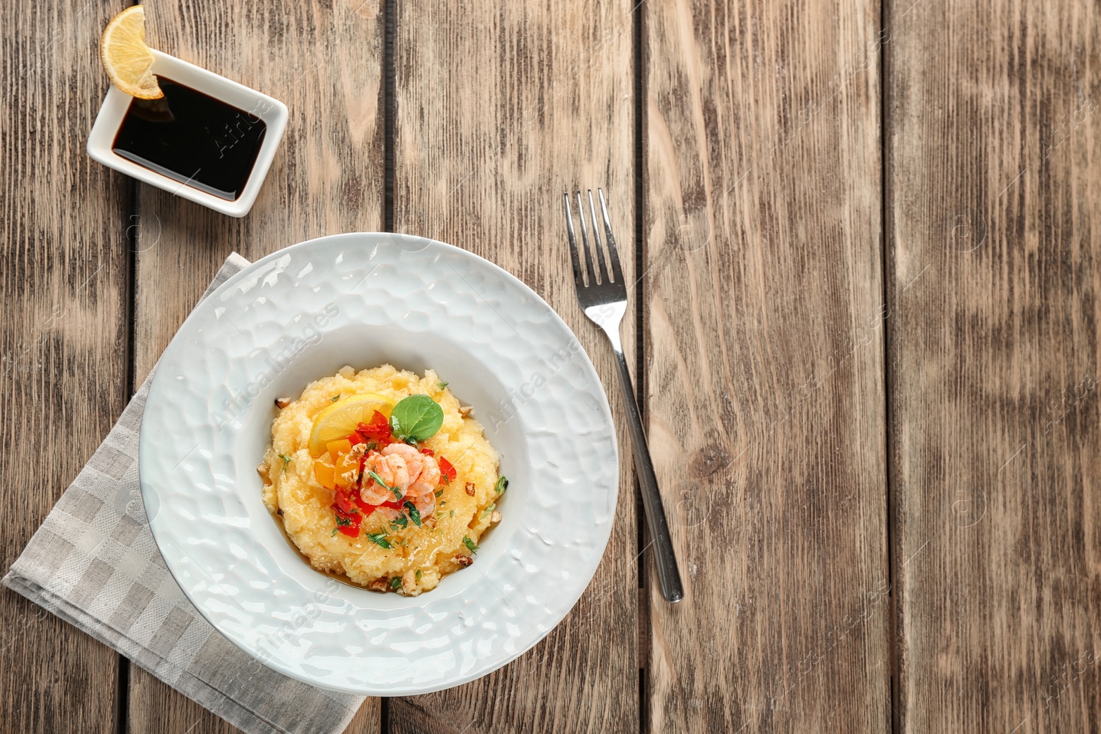 Photo of Plate with tasty shrimps and grits on table, top view