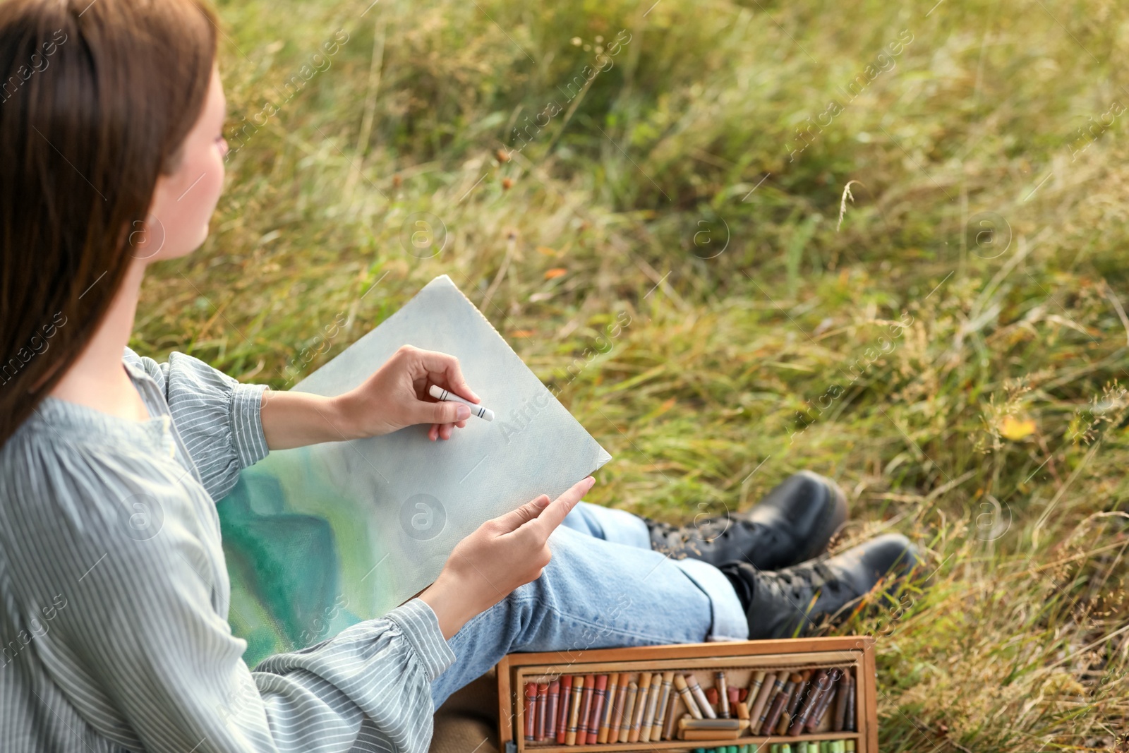 Photo of Young woman drawing landscape with soft pastels in nature. Space for text