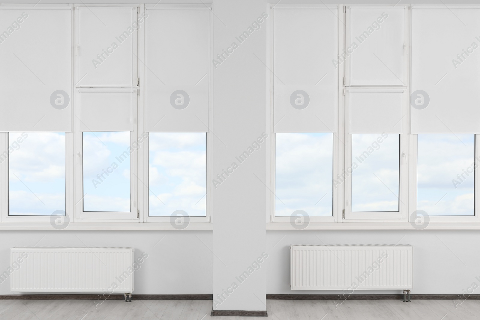 Photo of Plastic windows with white roller blinds indoors