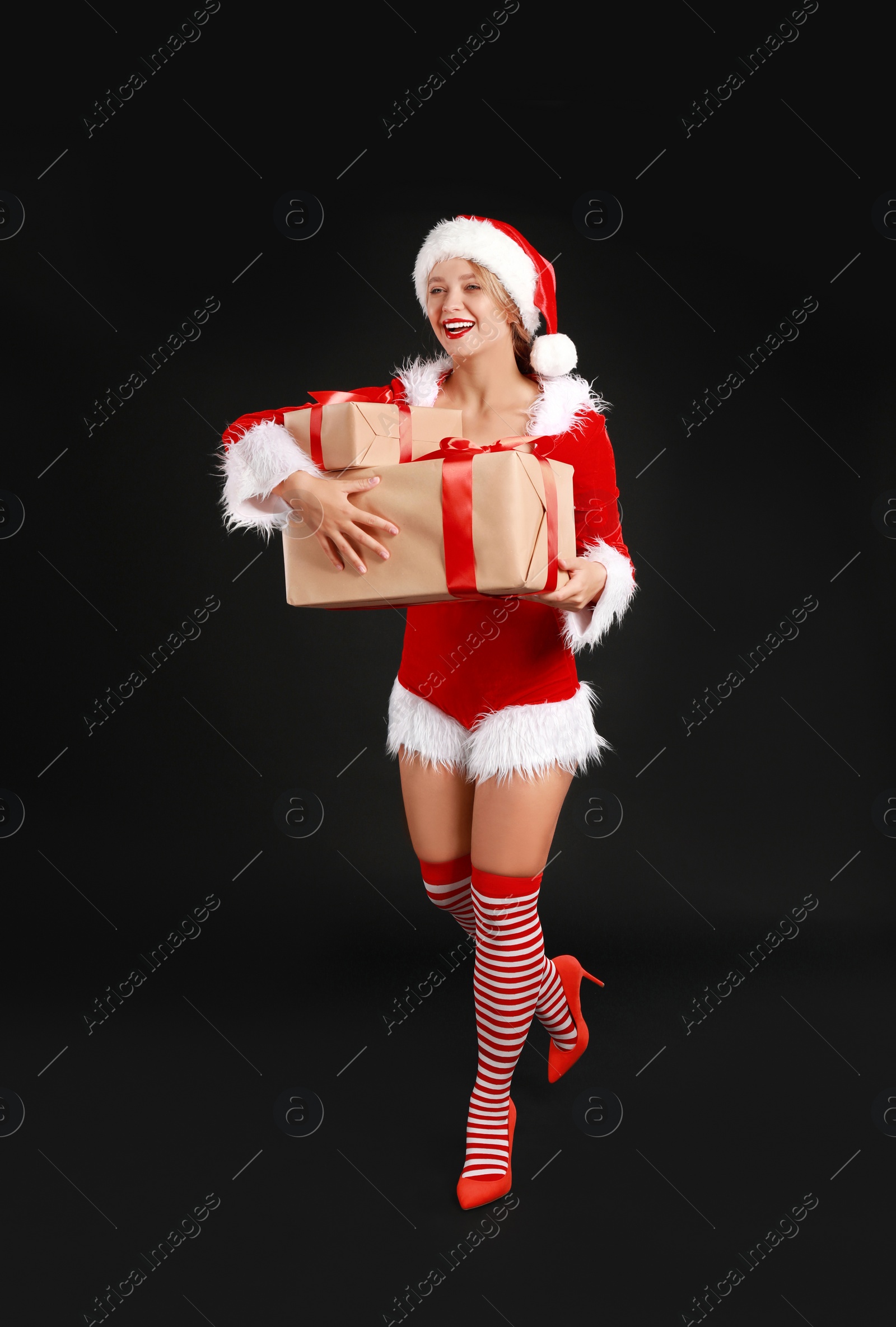 Photo of Beautiful Santa girl with Christmas gifts on black background