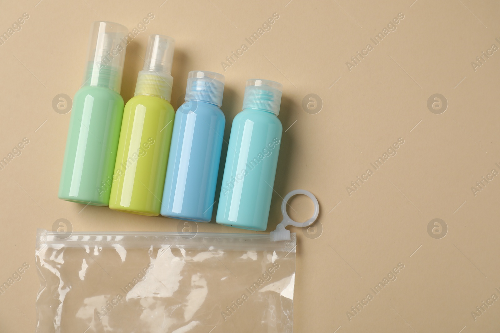 Photo of Cosmetic travel kit and plastic bag on beige background, flat lay with space for text. Bath accessories