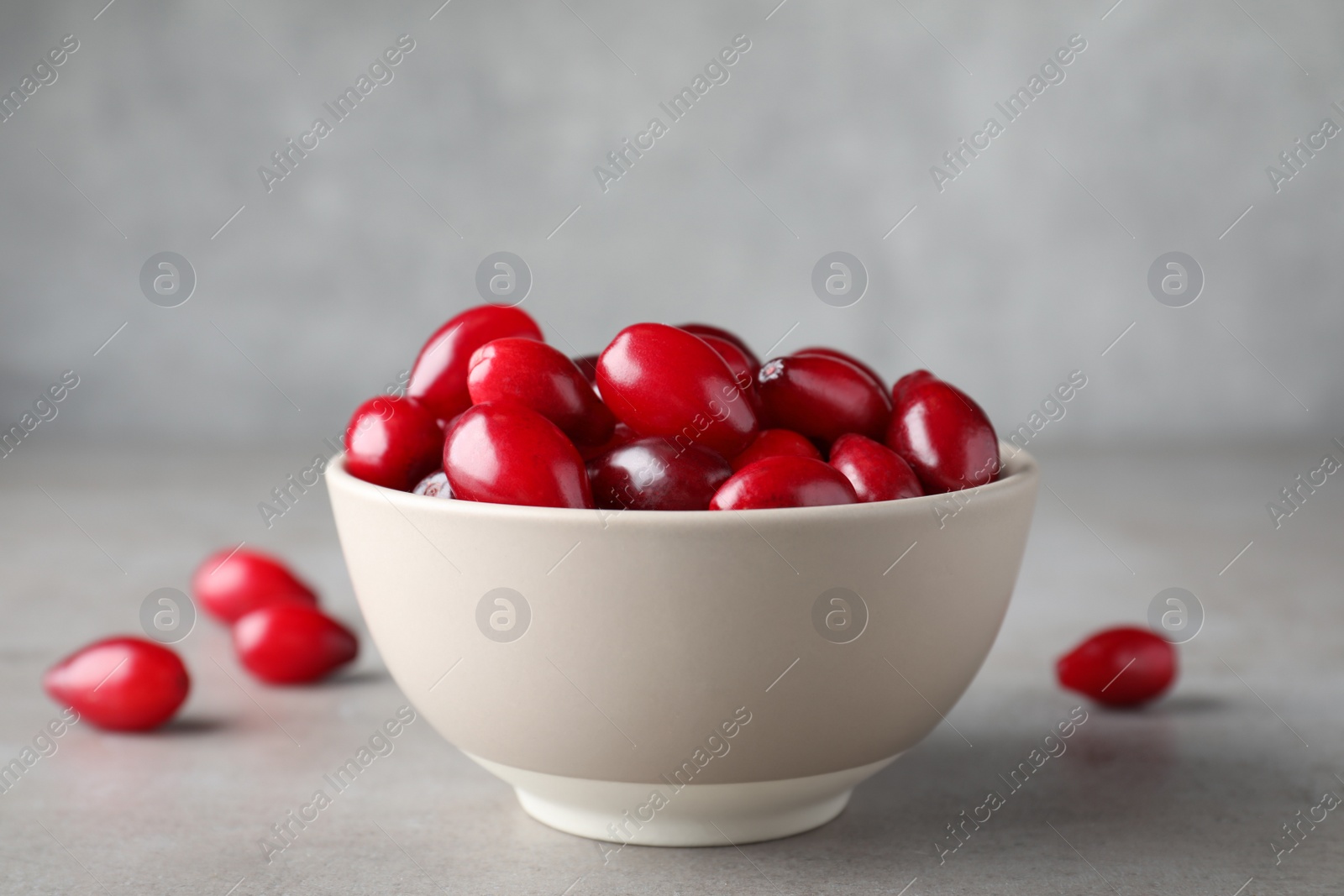 Photo of Fresh ripe dogwood berries in bowl on light grey table