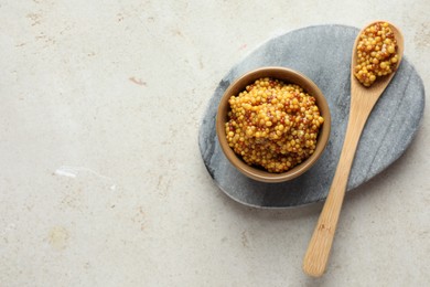 Photo of Bowl and spoon with whole grain mustard on light table, top view. Space for text