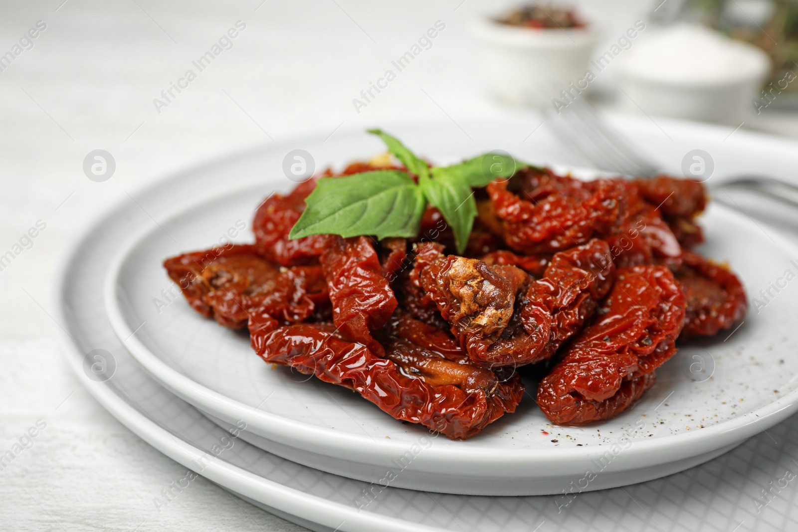 Photo of Plate with sun dried tomatoes on light table