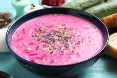 Photo of Delicious cold summer beet soup on light blue wooden table, closeup