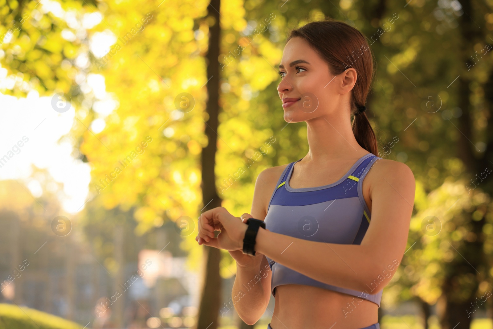 Photo of Attractive happy woman checking pulse after training in park on sunny day. Space for text