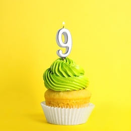 Birthday cupcake with number nine candle on yellow background