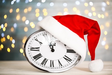 Photo of Clock with Santa hat showing five minutes until midnight on blurred background. New Year countdown
