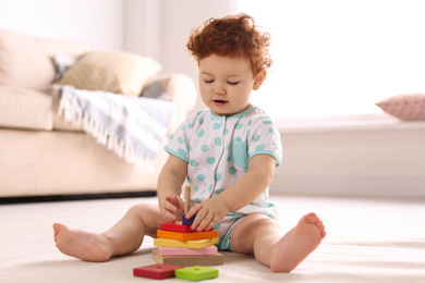 Photo of Cute little child playing with toy on floor at home