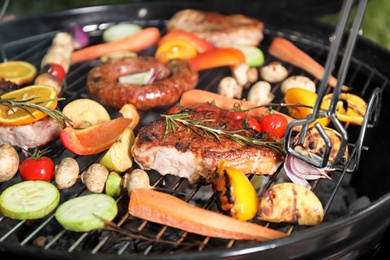 Photo of Barbecue grill with delicious cooked meat and vegetables, closeup