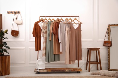 Photo of Stylish clothes hanging on rack in dressing room. Interior design