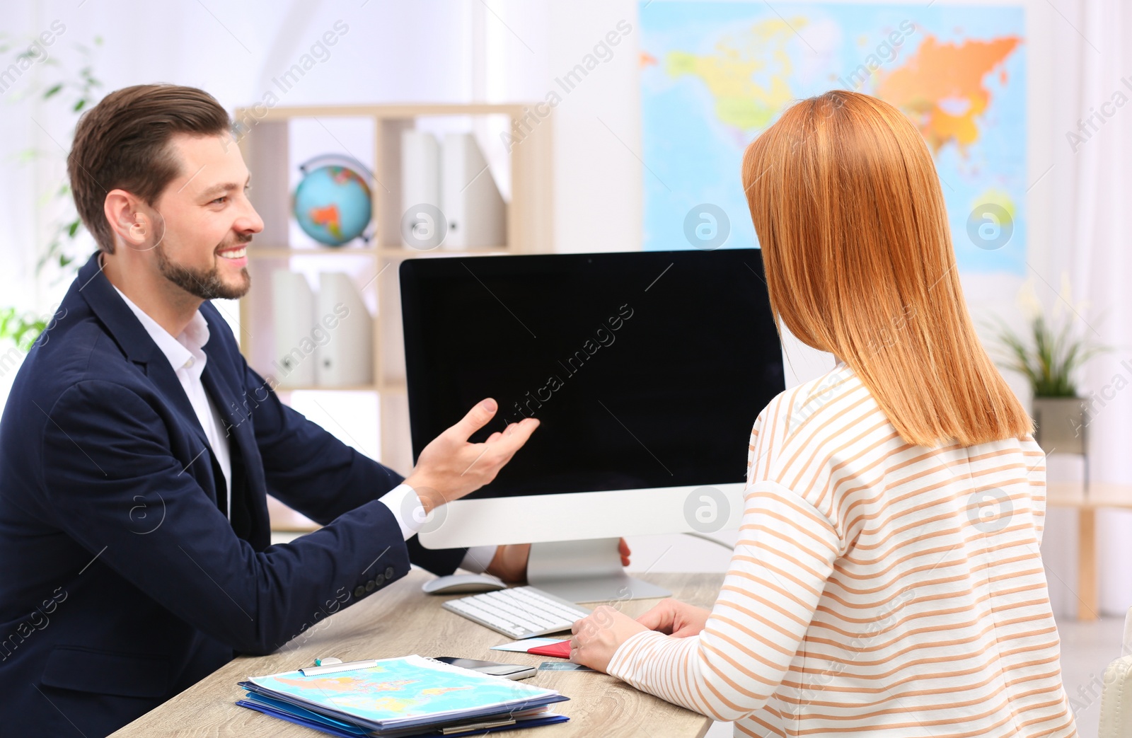 Photo of Male manager consulting client in travel agency