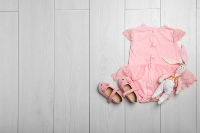 Flat lay composition with bodysuit and space for text on wooden background. Baby accessories