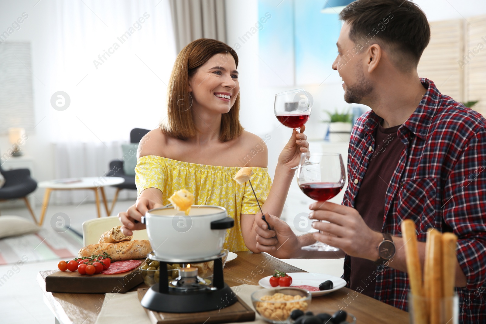 Photo of Happy couple enjoying fondue dinner at home