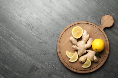 Photo of Fresh lemons and ginger on grey table, top view. Space for text