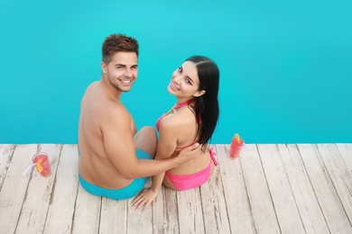 Photo of Woman in bikini with boyfriend near outdoor pool. Happy young couple