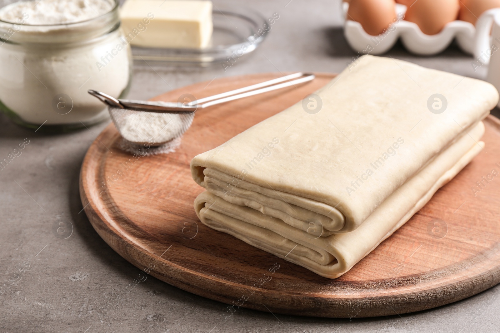 Photo of Composition with fresh dough on grey table, closeup. Puff pastry