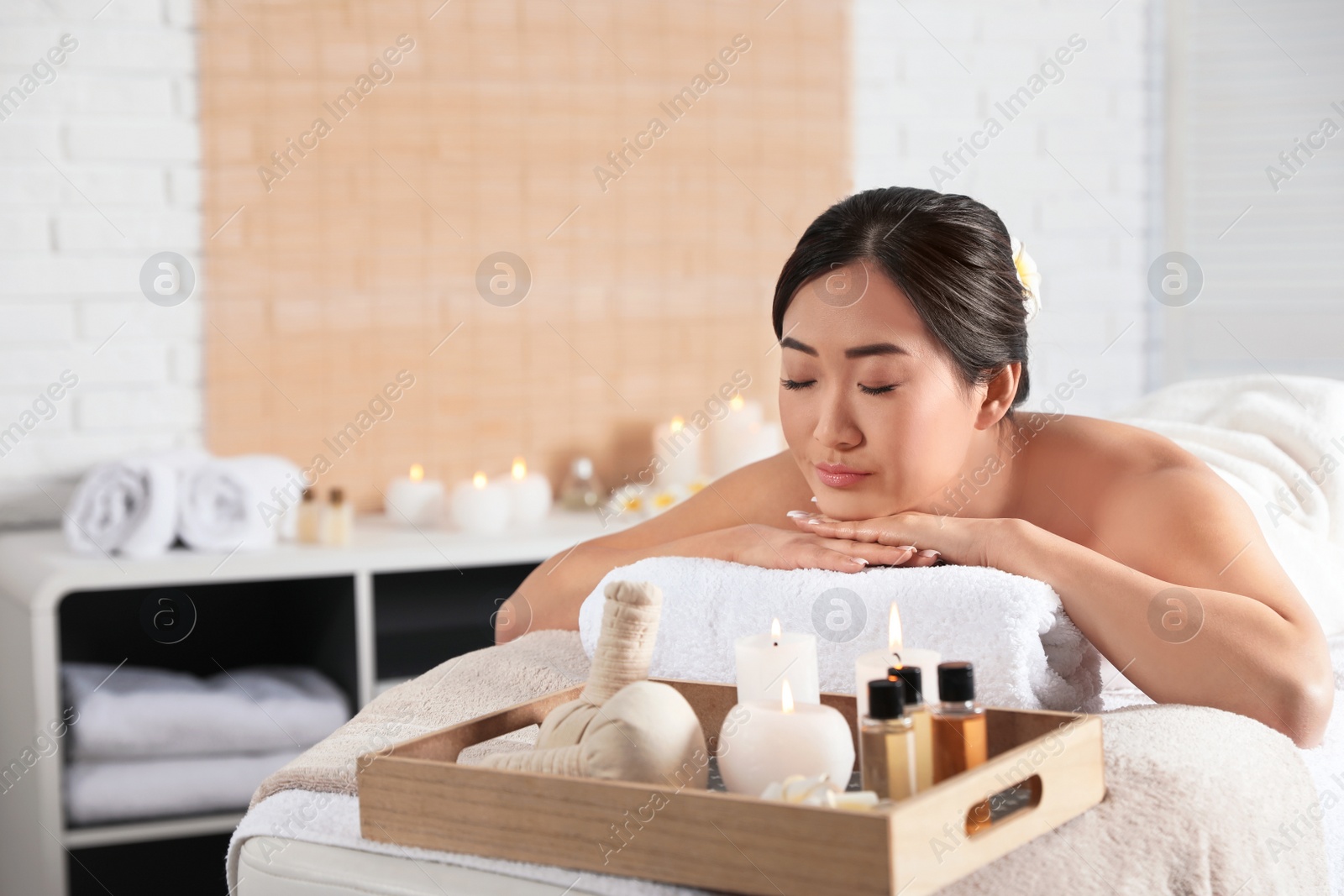 Photo of Beautiful Asian woman lying on massage table in spa salon. Space for text