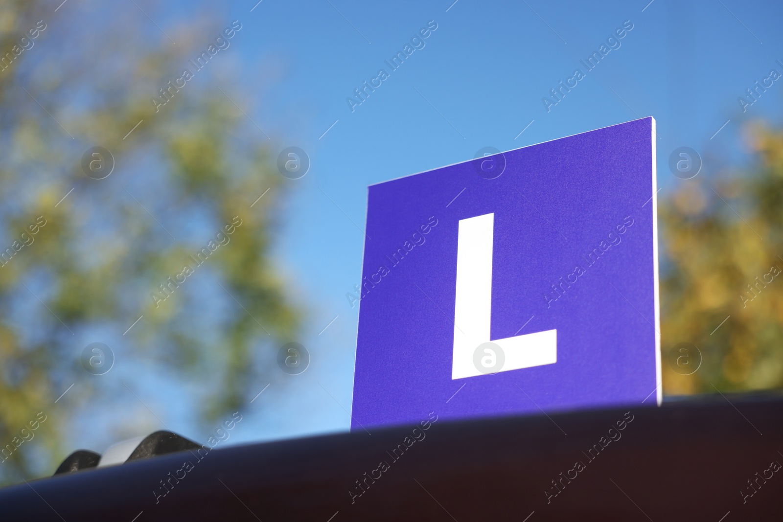 Photo of L-plate on car outdoors, space for text. Driving school