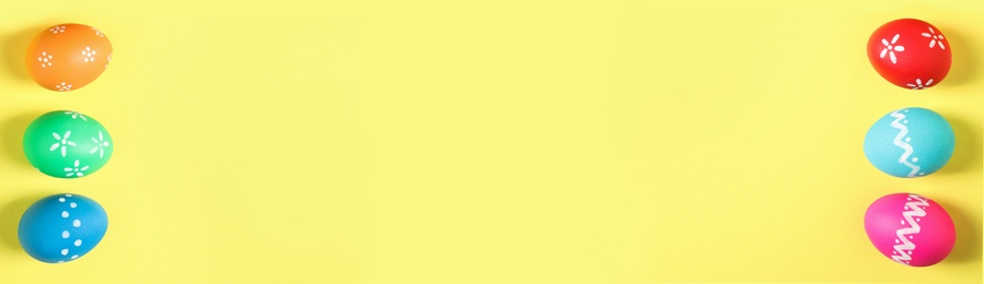 Image of Colorful Easter eggs and space for text on yellow background, flat lay. Horizontal banner design