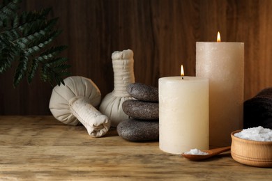 Photo of Beautiful spa composition with burning candles and sea salt on wooden table