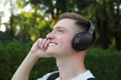 Photo of Smiling man in headphones listening to music in park