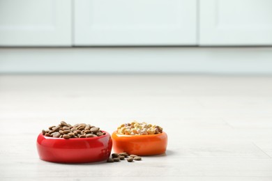 Bowls with dry dog food on white floor indoors, space for text