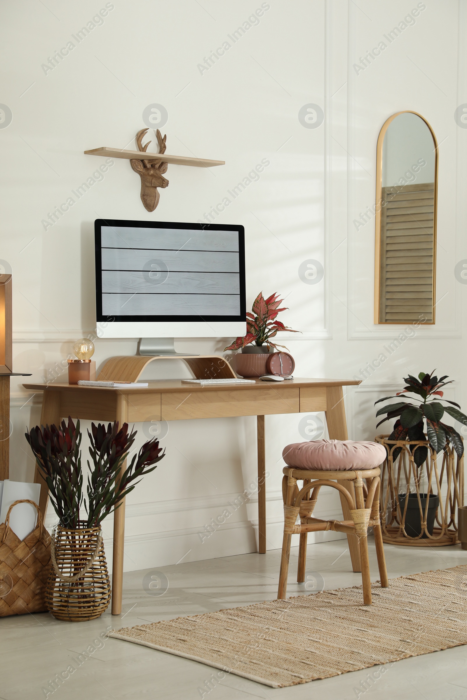 Photo of Comfortable workplace with modern computer and beautiful plants in room. Interior design