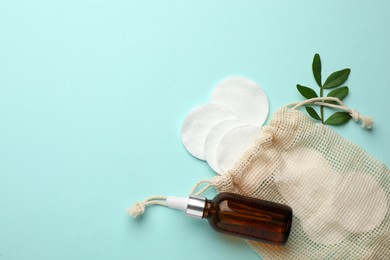 Photo of Cotton pads, leaf and makeup removal product on light blue background, flat lay. Space for text