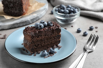 Photo of Delicious fresh chocolate cake served with blueberries on grey table