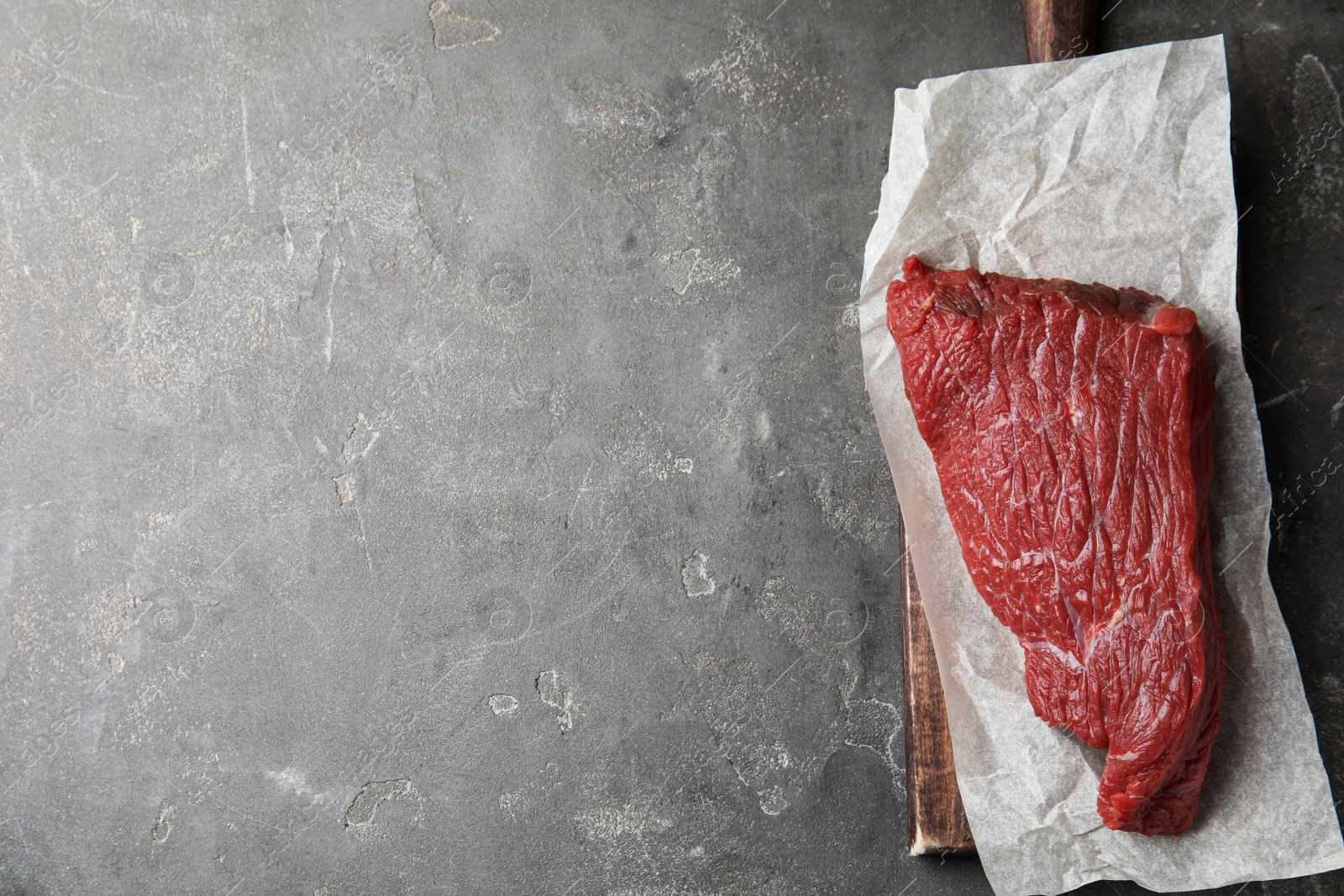 Photo of Fresh raw beef cut on grey table, top view. Space for text