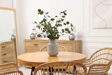 Photo of Dining room interior with comfortable furniture and eucalyptus branches