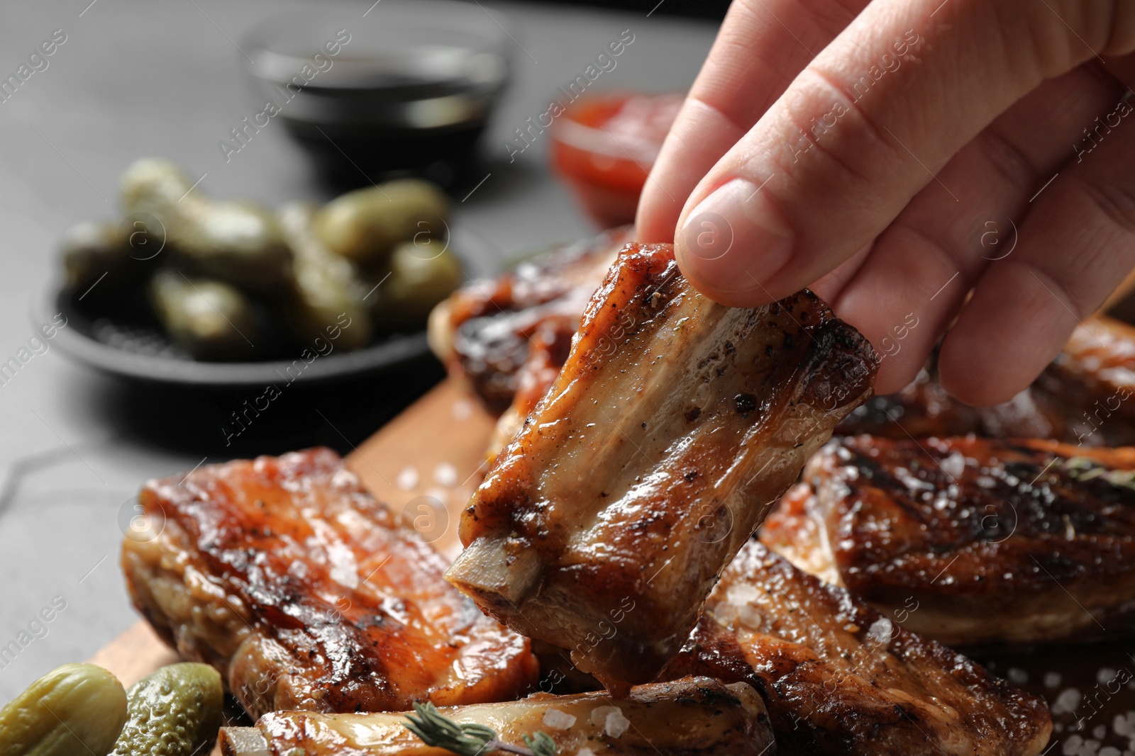 Photo of Woman with tasty grilled ribs at table, closeup