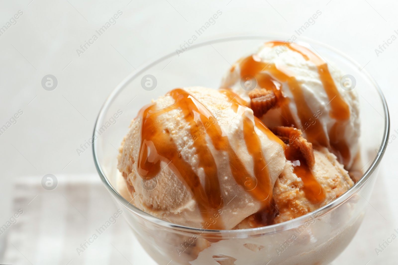 Photo of Bowl with caramel ice cream on light background