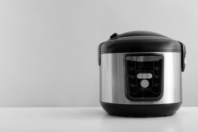 Photo of Modern electric multi cooker on table against grey background. Space for text